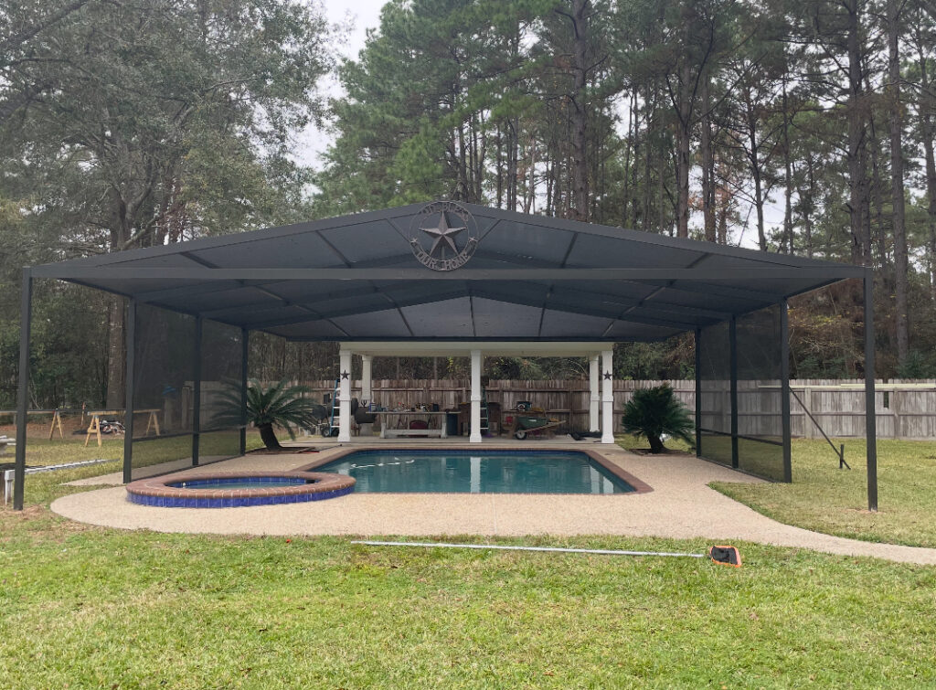 Solid-roofed black metal-frame screened pool cage over a pool and spa.