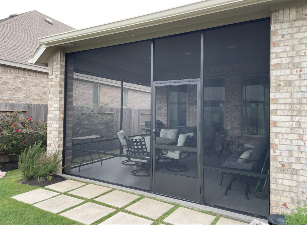 Stylish outdoor seating area enclosed with dark mesh screen panels by Metal Masons, perfect for bug-free entertaining in Conroe, TX.

